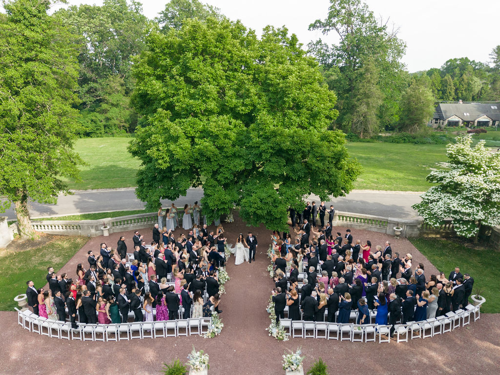 Couple hold hands and walk down aisle together at Elkins Estate wedding ceremony