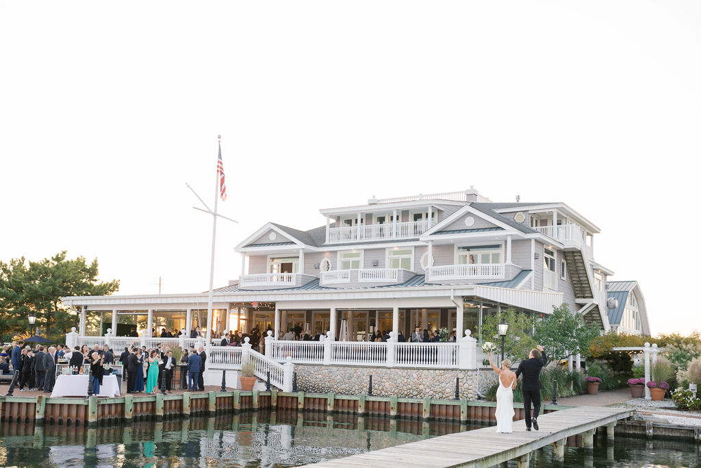 Bride and groom walk along pier to wedding reception at Bonnet Island Estate