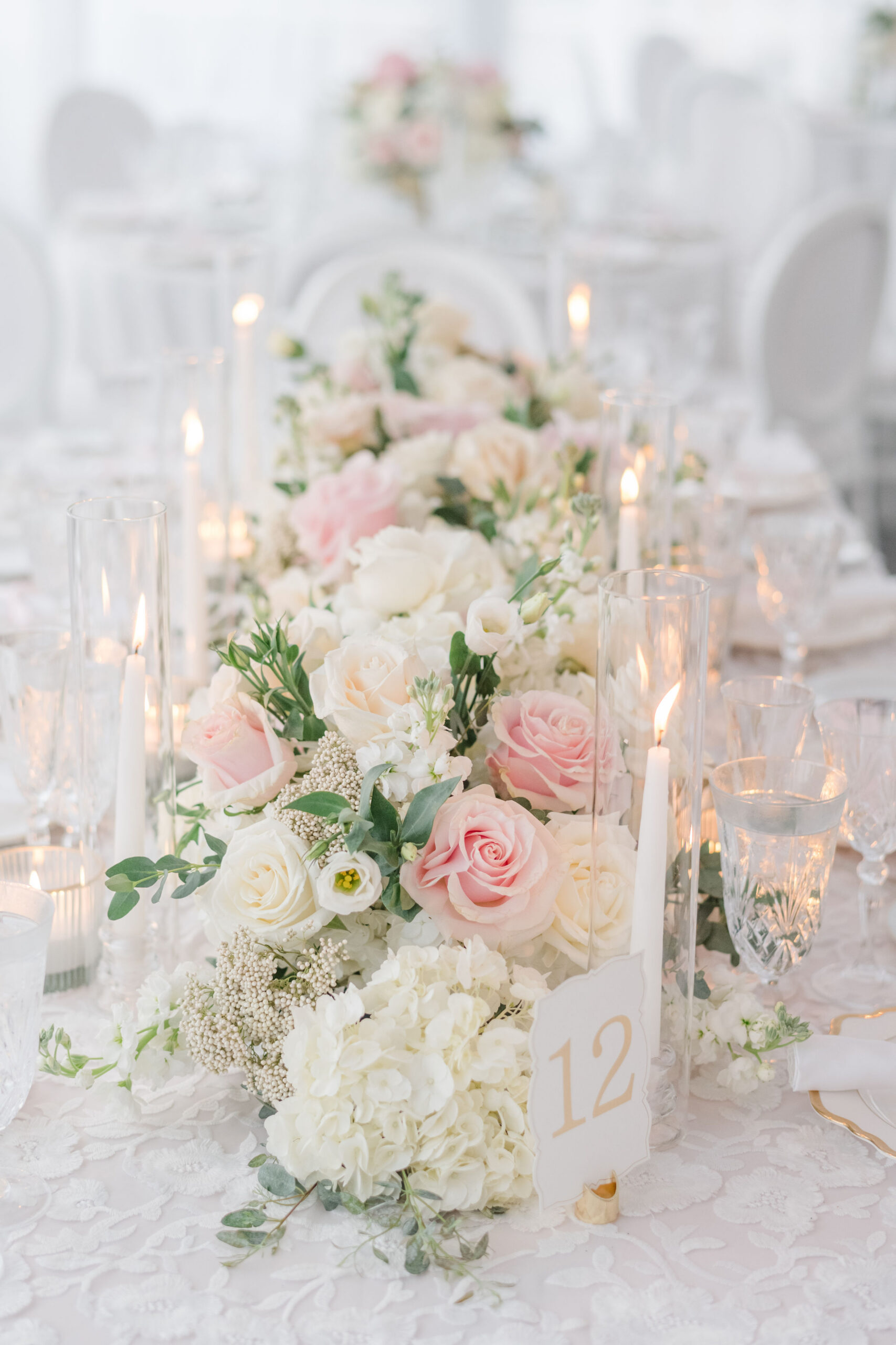 Pink and white florals with candles set on guests tables at Cairnwood Estate wedding